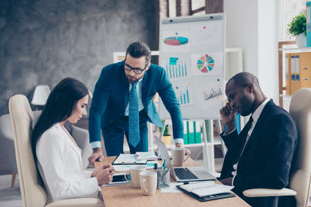 Stylish, handsome, attractive, dissatisfied unhappy man in glasses having problem with his colleagues, they did not reach a consensus, working routine, process in work station, placeの写真素材