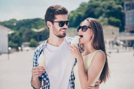 Stylish trendy man hugging his lover looking at tempting seductive woman licking biting sweet tasty...