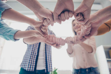 Progress, motivation, deal, agreement, achievement, handshake, diversity concept. bottom view low angle cropped portrait of business people hands putting their fists together in a circleの写真素材