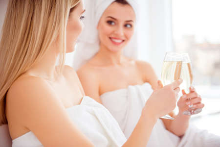 Cropped close up portrait of joyful, cheerful models after shower, bath having glasses with sparkling wine in hands, clinking, celebrating holiday, event, having fun, enjoying gathering meetingの写真素材