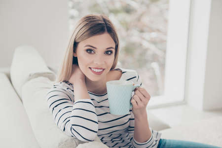 Portrait of cheerful, pretty, cute, lovely, nice girl with hairstyle, in striped outfit, having cup...