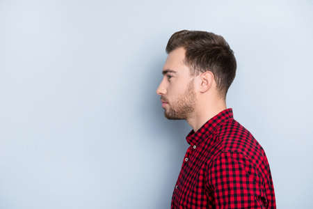 Half-faced close up portrait of  handsome serious focused concentrated manager looking aside thinking about career wearing checkered red clothes isolated on gray background copy-spaceの写真素材