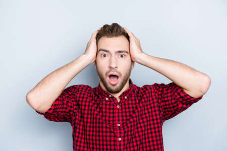 So unexpected and incredible! Embarrassed mixed-up confused unlucky person clothed in red checkered casual shirt, he is touching his head doesn't understand the situation, isolated on gray backgroundの写真素材