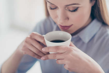 Close up cropped portrait of charming, pretty, nice, cute woman holding mug of aromatic coffee near...