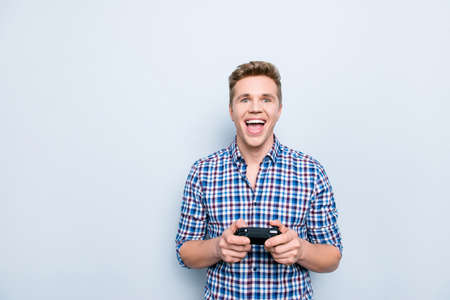 People leisure freetime holidays concept. Portrait of mad satisfied rejoicing delightful handsome excited cheerful man using controller for playing video games isolated on gray background copy-spaceの写真素材
