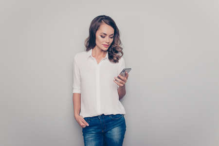 Portrait with copy space empty place of nice, cute, trendy, charming, pretty positive woman having smart phone checking email searching contact using wi-fi 5G internet isolated on grey backgroundの写真素材