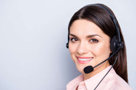 Close up portrait with copy space empty place of pretty cute friendly cheerful positive woman with headset microphone on head isolated over grey background looking at camera, advertisement conceptの写真素材