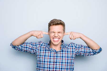 Silent noise blue casual checkered shirt people person concept. Close up portrait of annoyed angry sad upset exhausted guy doesn't want to listen to neighbor's music isolated on gray backgroundの写真素材