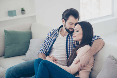 Portrait of stylish trendy couple indoor, in flat, apartment sitting on sofa enjoying time with each...