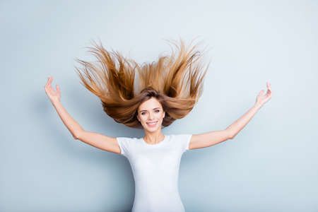 Portrait of funny positive girl blowing her long hair isolated on grey background looking at camera. Energy life fun time conceptの写真素材