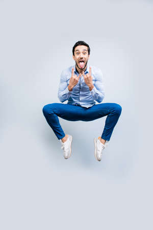 Portrait of crazy man funny creative guy in jeans sneakers jumping in air gesturing rock and roll...