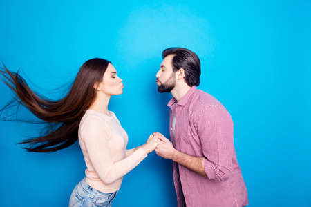 Profile portrait of stylish trendy couple keeping eyes closed holding hands kissing with pout lips...
