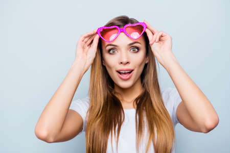 Portrait with copy space, empty place of impressed wondered girl raised her pink glasses in heart...