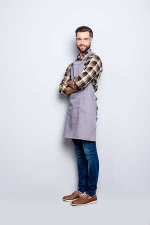 Full size body snap portrait of attractive cheerful carpenter with hairstyle in safety glasses jeans, looking at camera having his arms crossed isolated on grey backgroundの写真素材