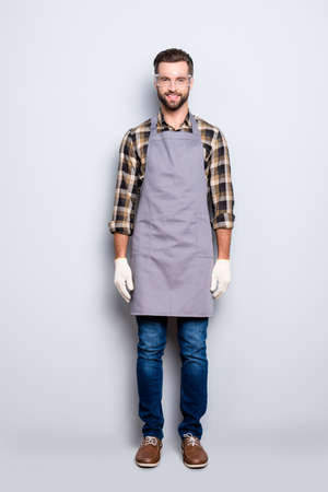 Full size, fullbody portrait of handsome attractive carpenter with hairstyle in safaty glasses  jeans, looking at camera isolated on grey backgroundの写真素材