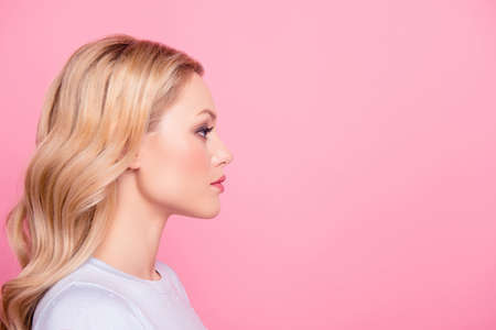 Profile side view portrait with copyspace empty place for product of  serious concentrated girl with modern hairdo isolated on pink background. Advertisement conceptの写真素材