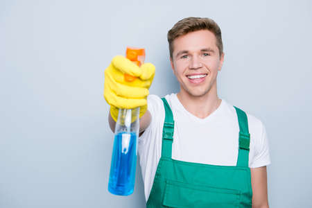 Household furniture person profession occupation concept. Close up portrait of excited cheerful glad handsome cleaner using spray for removing dirt from window isolated gray background selective focusの写真素材