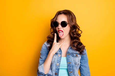 Portrait of crazy cool fashionable girl in summer glasses gesturing tongue out showing rock and roll...