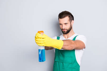 Portrait of funny comic cleaner in uniform t-shirt overall with stubble holding detergent spray with...