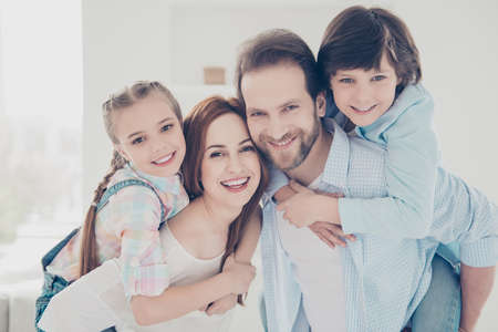 Head shot portrait of full family, cheerful parents holding on back in piggyback style two kids, handsome dad with stubble beautiful mom sweet children enjoying time together. Affection conceptの写真素材