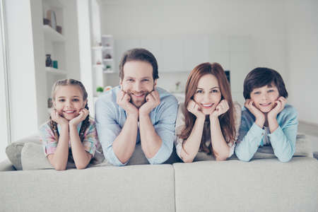 Portrait of positive attractive family with two kids beautiful girls handsome men enjoying free time together indoor in modern white flat looking at camera having beaming smilesの写真素材