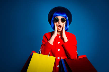 Portrait of chocked woman with wide open mouth having problem holding colorful packets waste all...