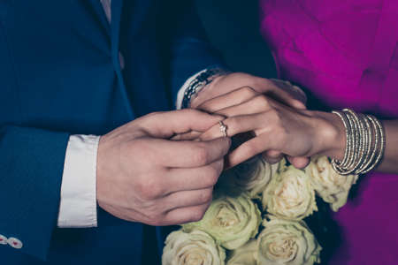 Cropped close up portrait of trendy rich gentleman mr in suit putting on engagement ring accessories...