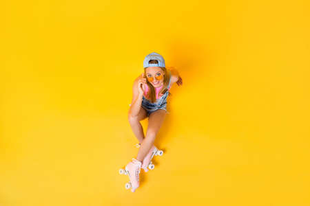 Top view portrait of funky positive girl looking out glasses on face sitting on floor ground isolated on yellow background, wellness fitness athletic workout conceptの写真素材