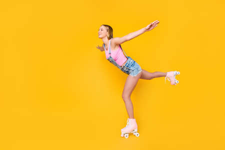Side view profile portrait of cheerful positive girl riding on roller skates making swallow figure...