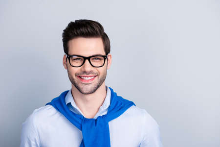 Portrait with copy space of cute nice guy with tied blue pullover around the neck, isolated on grey backgroundの写真素材