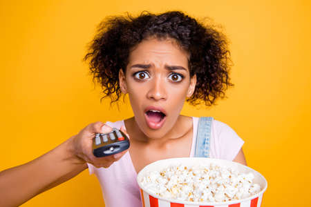 WTF! Head shot portrait of sad upset girl using remote controller having bucket with pop corn missed...