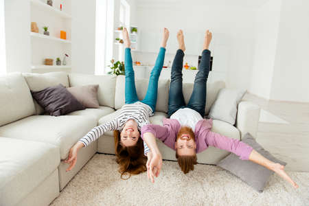 Coziness holiday house friendship funny partners lifestyle leisure concept. Excited cheerful joyful funky rejoicing lovers fooling around lying on divan in living room wearing casual outfit clothesの写真素材