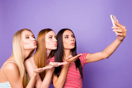 Portrait of lovely romantic trio using smart phone sending air kiss with pout lips palms shooting...
