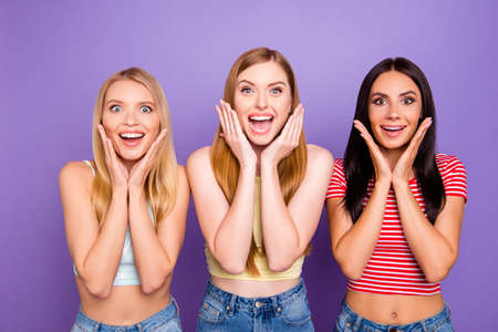 Luck success concept. Portrait of amazed wondered girls holding palms hear cheeks with wide open mouth eyes looking at camera isolated on violet background. Rest relax leisure conceptの写真素材