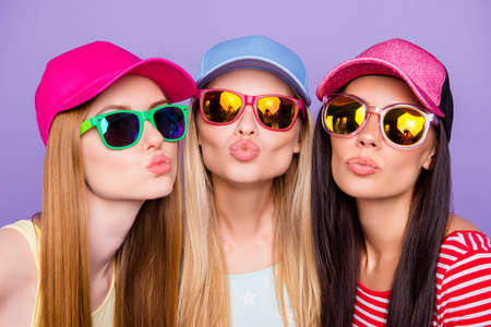 Head shot portrait of lovely sweet trio, blonde brunette ginger sending kiss with pout lips at camera isolated on vivid violet backgroundの写真素材