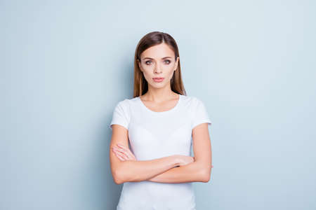 Portrait of perfect cute girl in white t-shirt having holding arms crossed isolated on grey background looking at cameraの写真素材