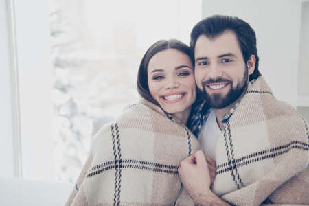 Portrait of romantic lovely couple covered with blanket looking at camera cheek to cheek. Rrue feelings harmony idyllic delight conceptの写真素材