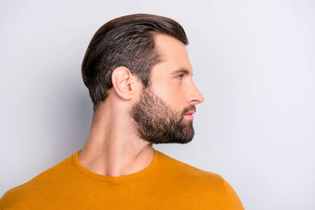 Close up profile side half-faced view portrait of handsome virile masculine brutal with trendy hairdress entrepreneur wearing color of mustard autumn sweater  isolated on gray background copyspaceの写真素材