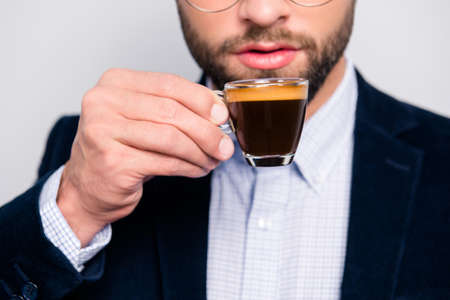 Cropped close up photo of tasty bitter fresh aromatic hot espresso in glass, confident smart wearing...