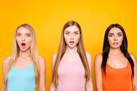 Portrait of shocked scared trio with wide open mouth eyes having negative unexpected expression isolated on bright yellow background.の写真素材