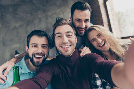 Self portrait of four attractive, confident, successful, funny guys with modern hairstyle making selfie with two hands on mobile phone, front camera, community spending great timeの写真素材