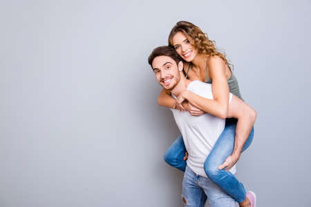 Portrait with copysapce of attractive lovely couple, strong man carrying on back charming woman with...