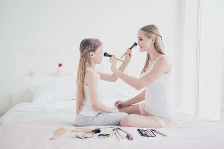 Long blonde hair teenager friendship studying concept. Side view photo portrait of beautiful cute cheerful funny pretty delightful attractive sweet girl sitting on linens doing make-upの写真素材