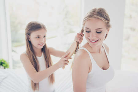 Fashion tenderness delight pleasure domestic life concept. Close up portrait of beautiful pretty kind calm gorgeous sisters spending time together inside the houseの写真素材