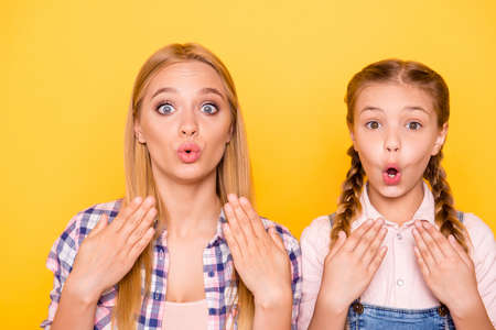 Close up portrait of two pretty lovely cute excited glad rejoicing impressed beautiful girls with blowing lips big eyes isolated on bright backgroundの写真素材