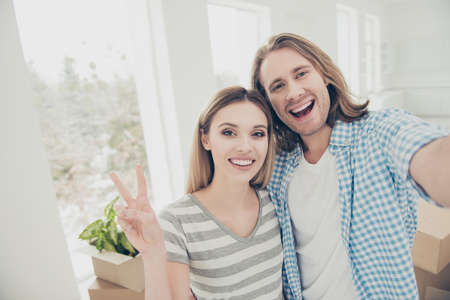 Mortgage relocation package new life large big loft window rent good day event concept. Close up picture glad cheerful emotional satisfied nice beautiful married couple making selfie against havingsの写真素材