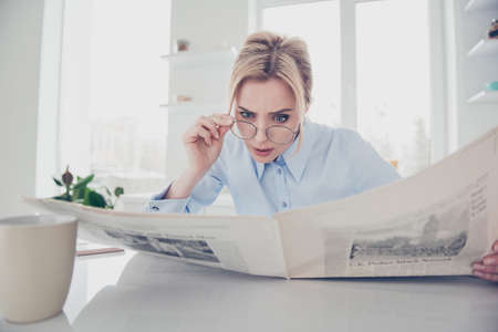 Adult adorable woman lady boss putting spectacles down keeping in hands and reading newspaper early...