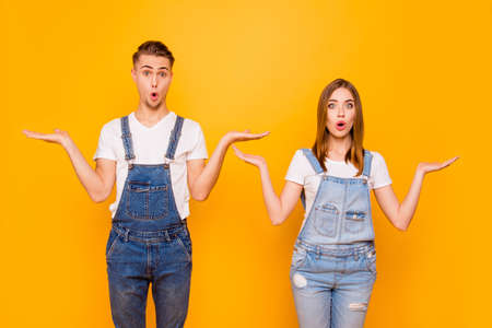 Portrait of cute young couple standing together, astonished with widely opened mouths, gesturing I...