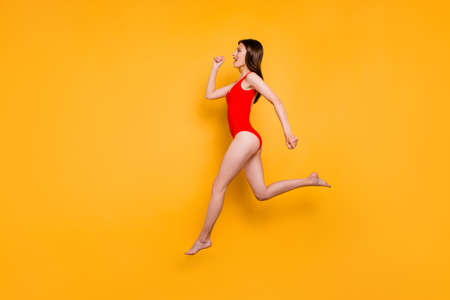 People life energy concept. Full-size portrait of fit sporty girl jumping over in the air isolated on yellow background with copy space for textの写真素材
