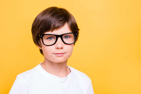 Portrait of attractive young cheerful caucasian school boy, wearing glasses, smiling over yellow...